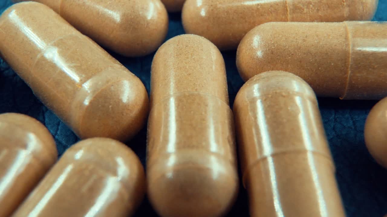 una cámara lenta macro tomada en un laboratorio de una cápsulas médicas, píldoras orgánicas, luz de estudio, 120 fps, video full hd