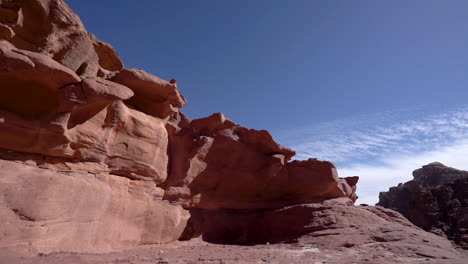 a timelapse of blue sky and clouds moving on a sunny day above red rock desert hill in wadi rum