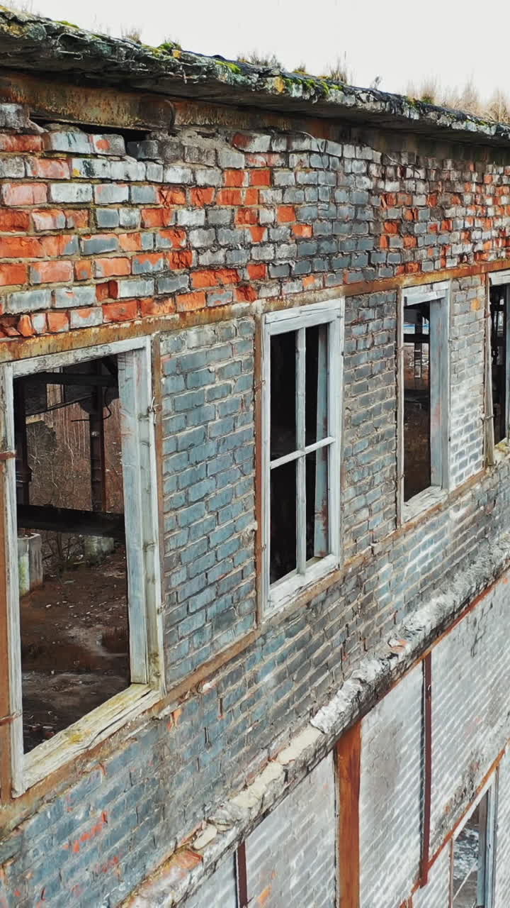 Aerial view of an old factory ruin and broken windows. Old industrial building for demolition. Vertical video