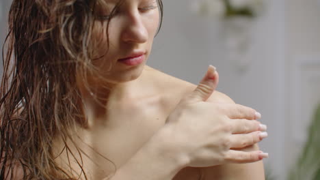 mujer aplicando loción corporal después de la ducha