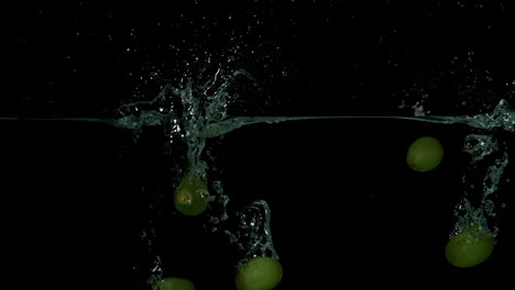 grapes falling in water on black background