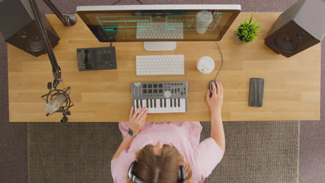 overhead view of female musician at workstation with keyboard and microphone in studio