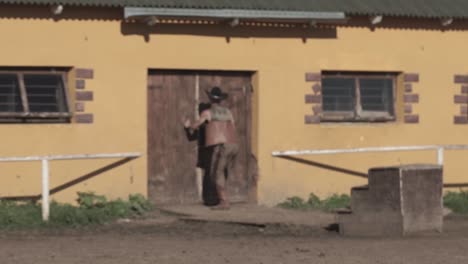 cowboy training a white horse at a stable