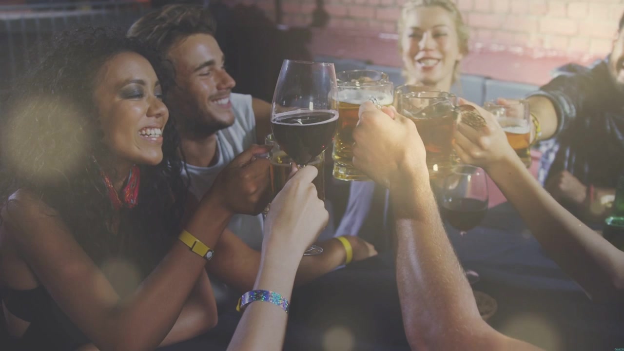 Gruppe voksne som tar med drinker i en bar, sentrerer ølkrus og vinglass for en skål.