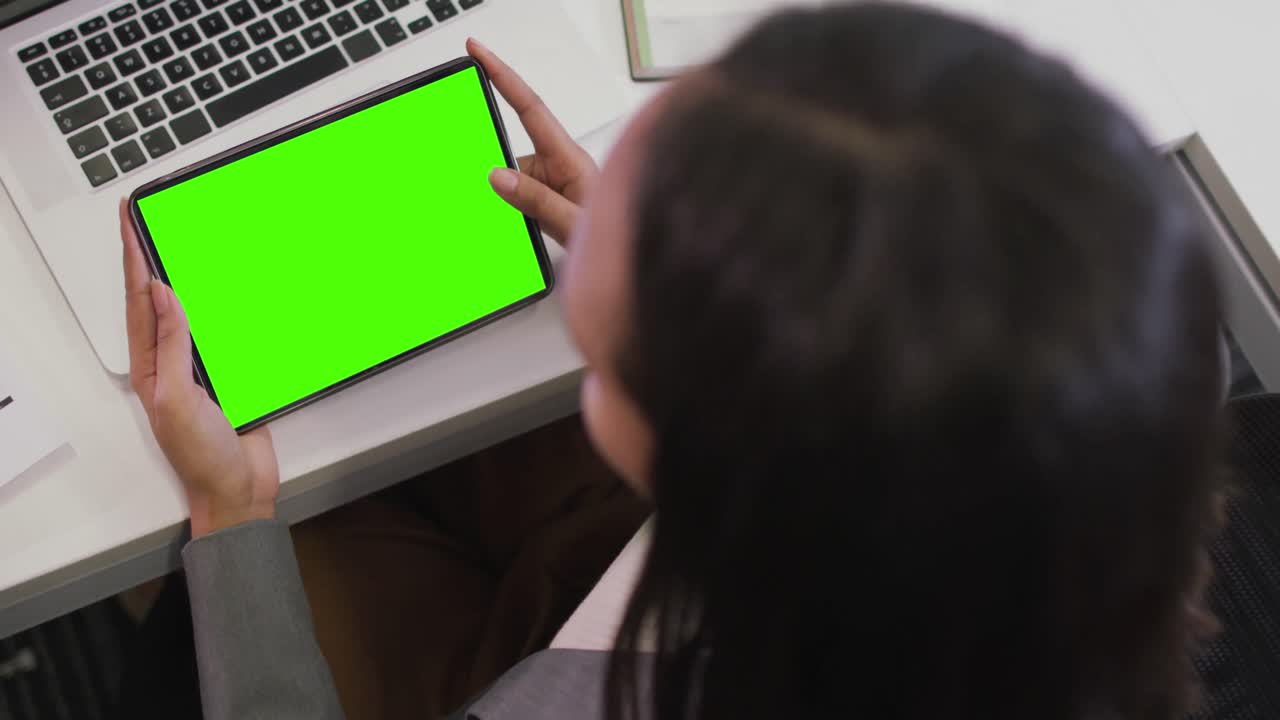 mujer de negocios biracial que usa una tableta para videollamadas con espacio para copiar