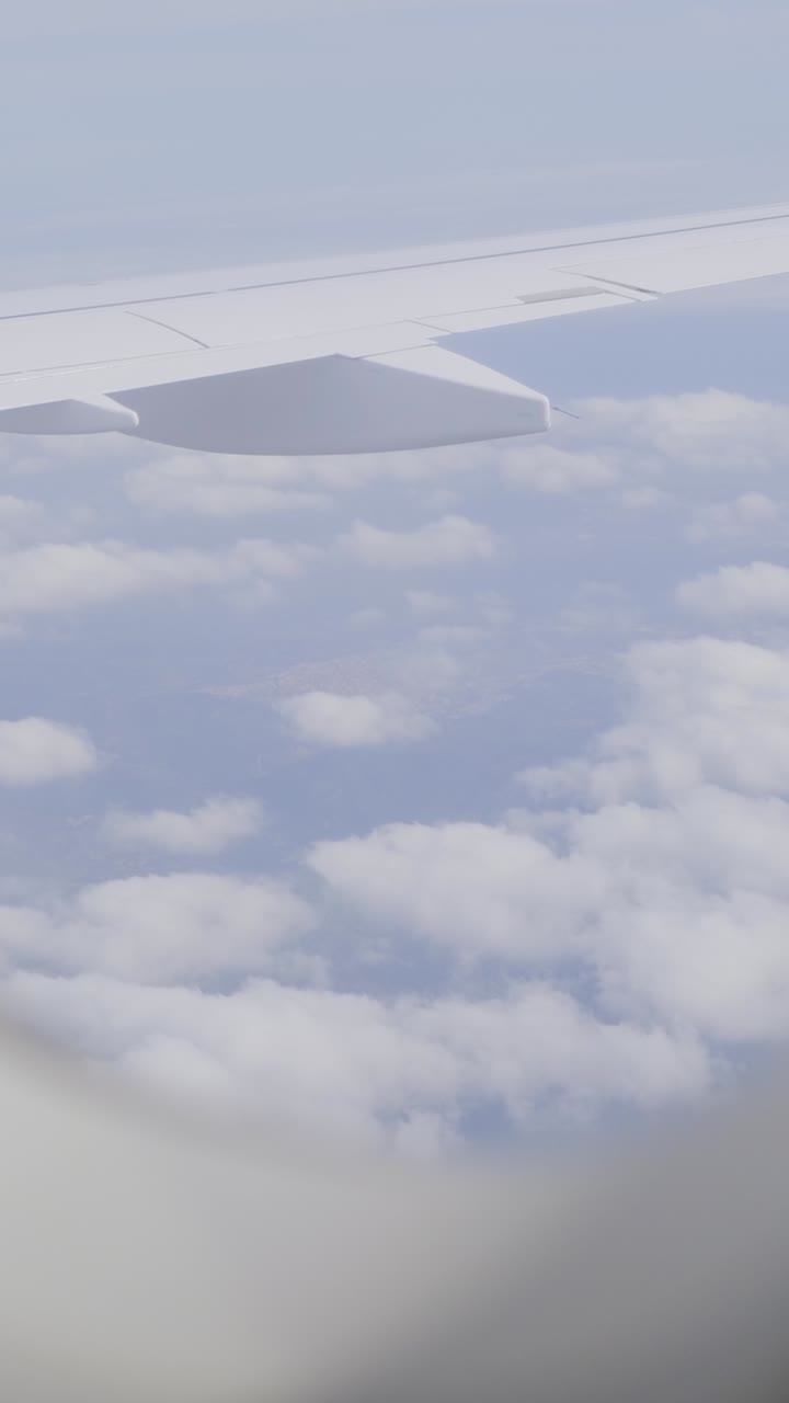 View from airplane window over fluffy clouds during daytime flight