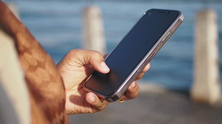 Frau nutzt Smartphone draußen am Meer