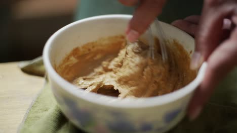 mantequilla de maní gruesa pasta hecha a mano batida en un cuenco, filmada de cerca en cámara lenta