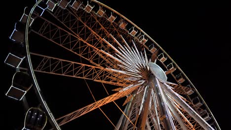 rueda gigante. una rueda gigante gira contra el fondo del cielo nocturno. primer plano de una rueda enorme con iluminación nocturna. construcción de rueda gigante iluminada girando contra el fondo oscuro del cielo nocturn.