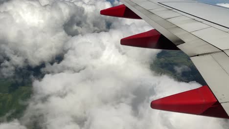 View-from-passenger-window-on-airplane-wing-and-white-puffy-clouds-in-the-sky