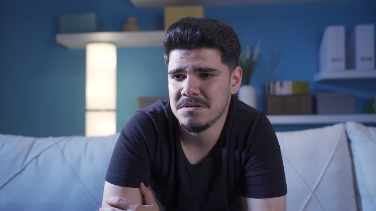 hombre emocionalmente solitario en casa con lágrimas en los ojos y llorando.