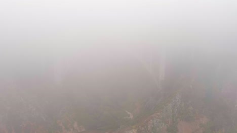 the bixby bridge on big sur's state route-1 is barely visible through the thick fog
