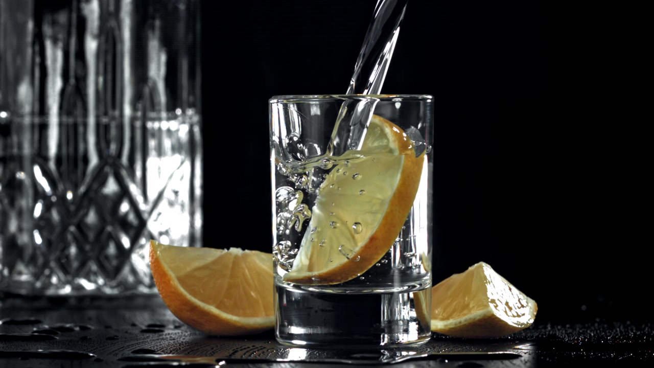 Cảnh quay chậm rót Vodka vào ly shot với chanh