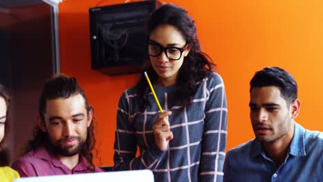 Smiling-graphic-designers-discussing-over-laptop-in-meeting