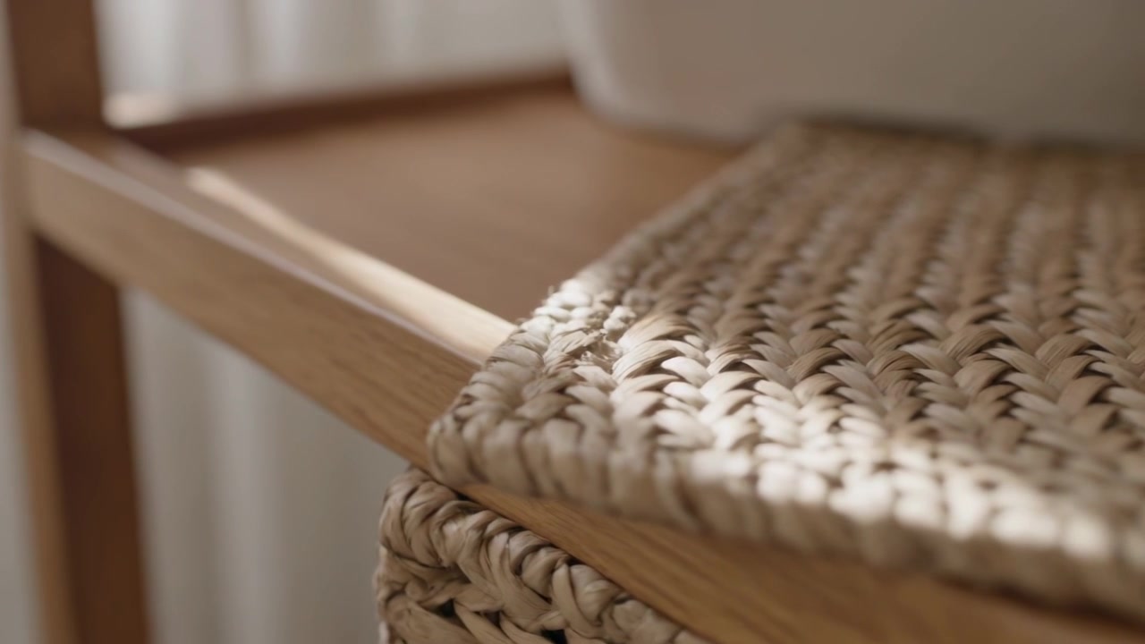 Inquadratura ampia che mostra una seduta in rattan intrecciato su una sedia di legno vicino a una finestra con tende e un vaso bianco