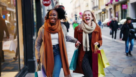 two happy women shopping on an urban street