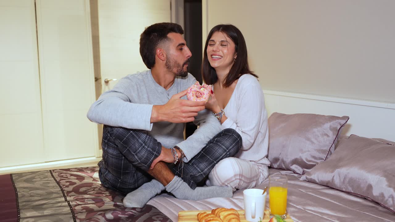 Coppia che si gode la colazione a letto con ciambelle