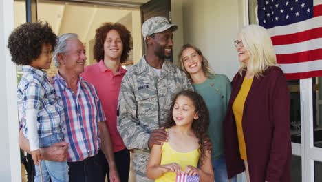 Video-of-happy-diverse-family-holding-usa-flags-standing-outside-of-house