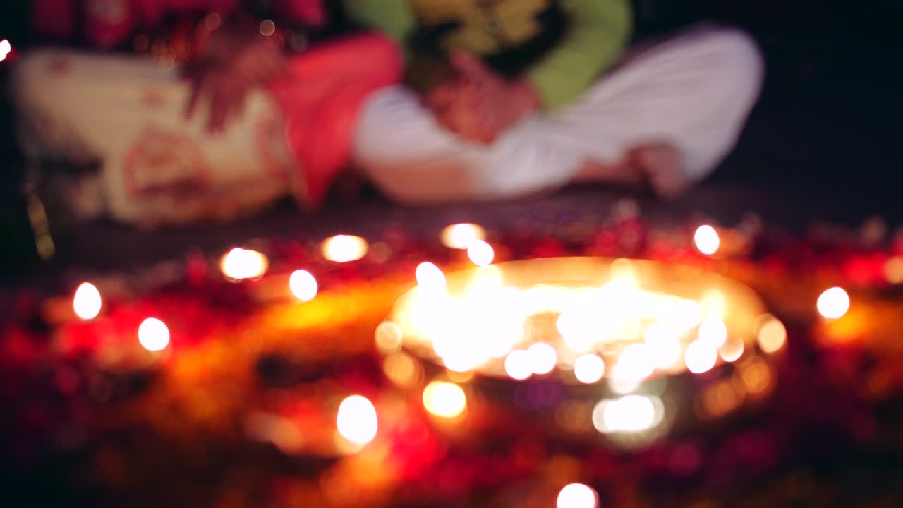 Una coppia celebra un colorato rangoli di Diwali - rosso, rosa, arancione, verde.