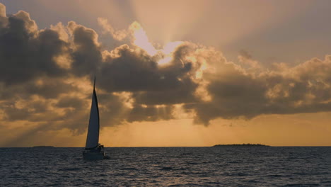 Velero-Contra-La-Brillante-Puesta-De-Sol-Naranja-Cerca-De-La-Isla-De-Los-Pinos,-Nueva-Caledonia