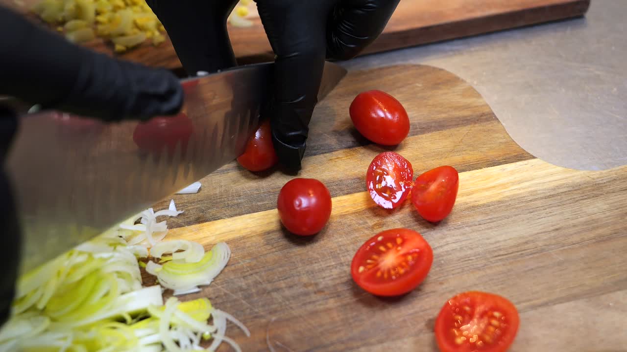 el chef corta los tomates cereza en cuñas en una tabla de cortar