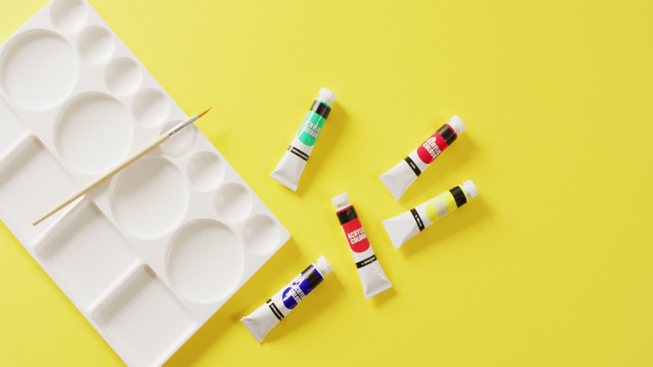 복사 공간과 함께 노란색 배경에 수색 페인트, 페인트 브러시 및 팔레트의 튜브의 비디오