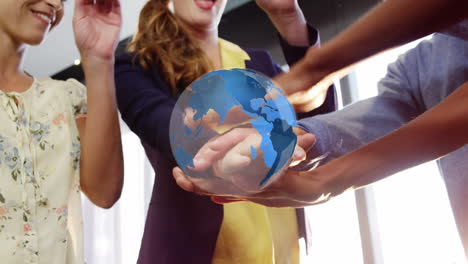 animation of globe rotating over happy diverse colleagues stacking hands at casual office meeting