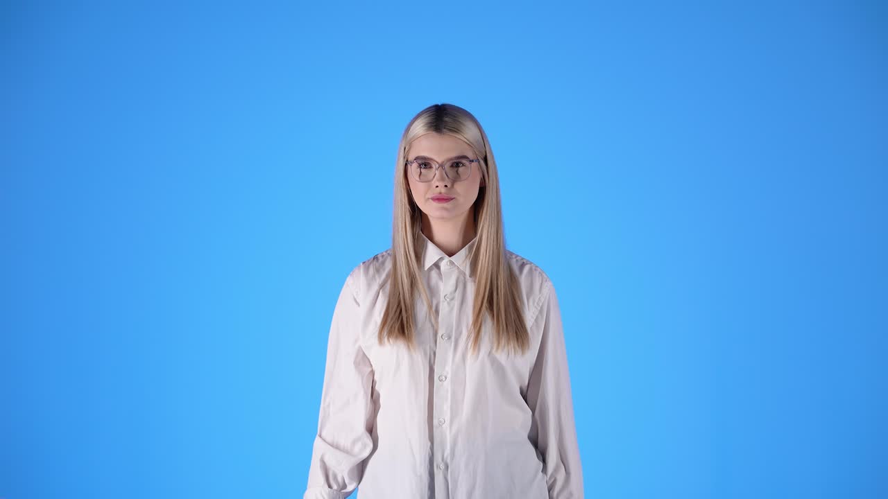 Donna con camicia bianca mostra il pollice in su, concetto di approvazione, scatto in studio.