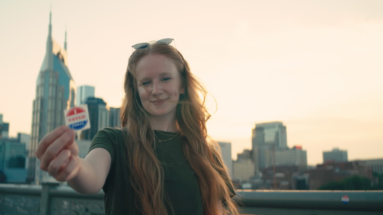 Woman proudly displays 'I Voted' sticker in front of a city skyline