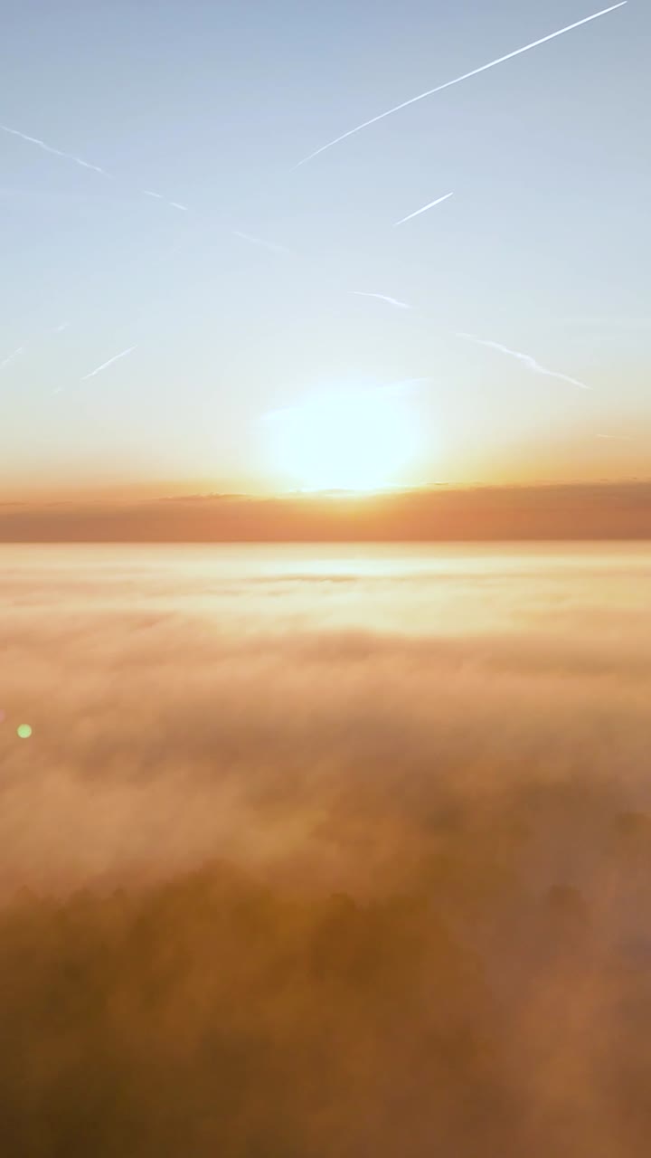 Sunrise or Sunset Over a Sea of Clouds with Contrails in the Sky