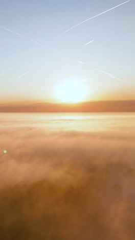 sunrise or sunset over a sea of clouds with contrails in the sky