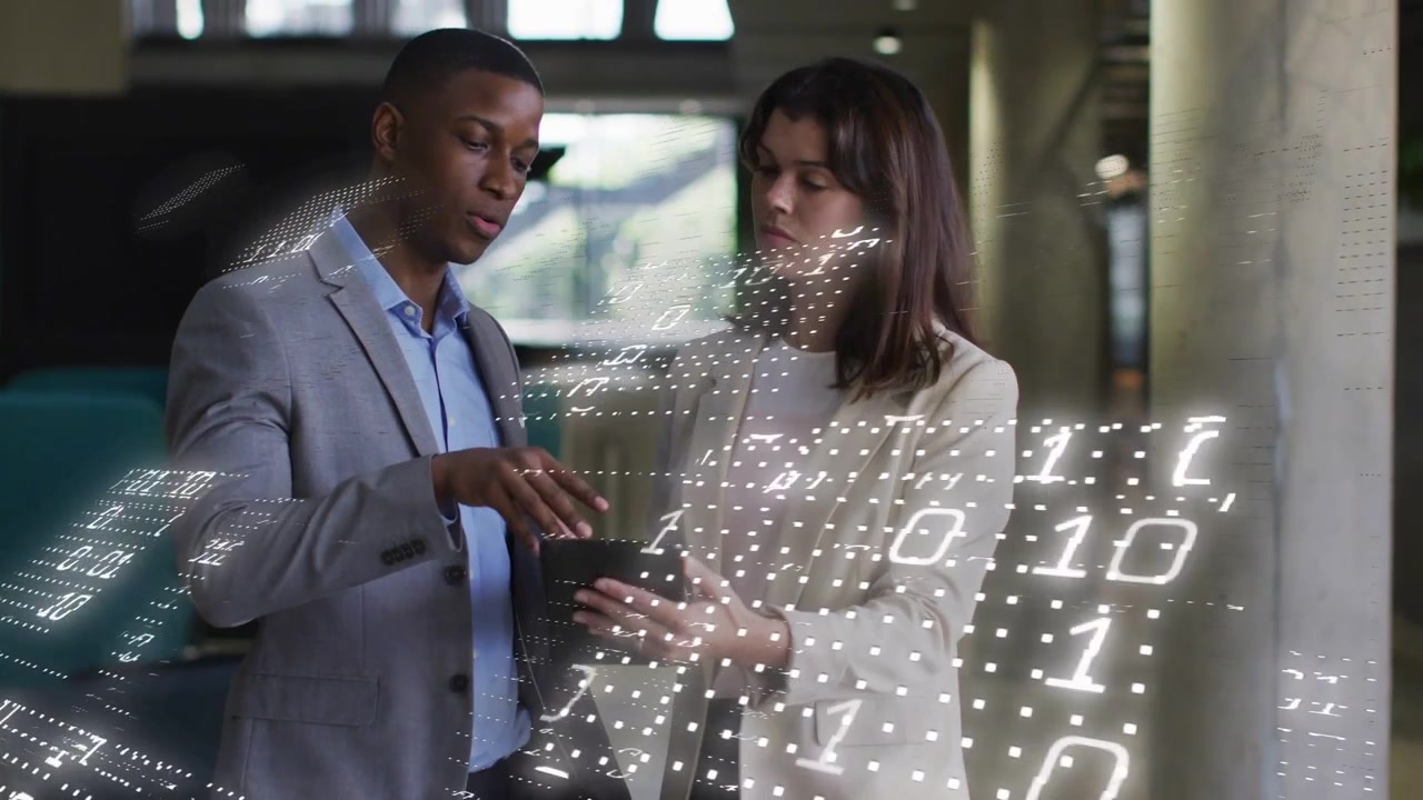 Homme pointant et faisant glisser sur une tablette tandis qu'une femme tient et examine des données commerciales avec une superposition binaire
