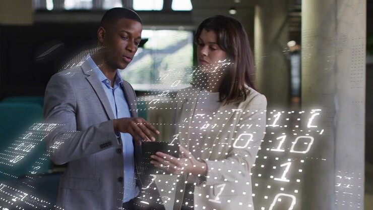 Man pointing and swiping tablet while woman holding and reviewing business data with binary overlay