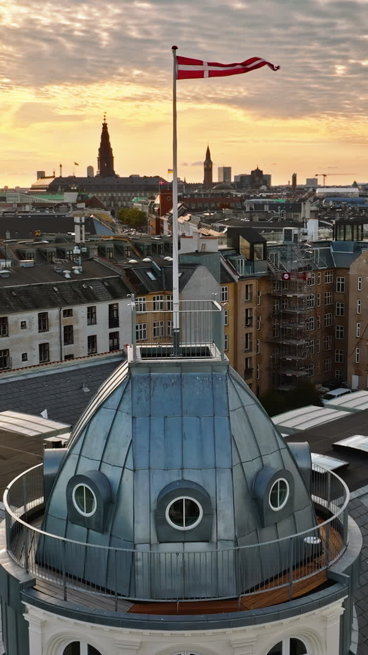 Aerial drone view of the Danish flag waving on top of a building in Copenhagen. Vertical
