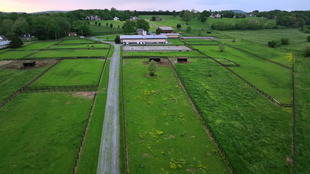 Aerial approaching shot of green fields of american horse farm in rural area. Cloudy day in spring season.