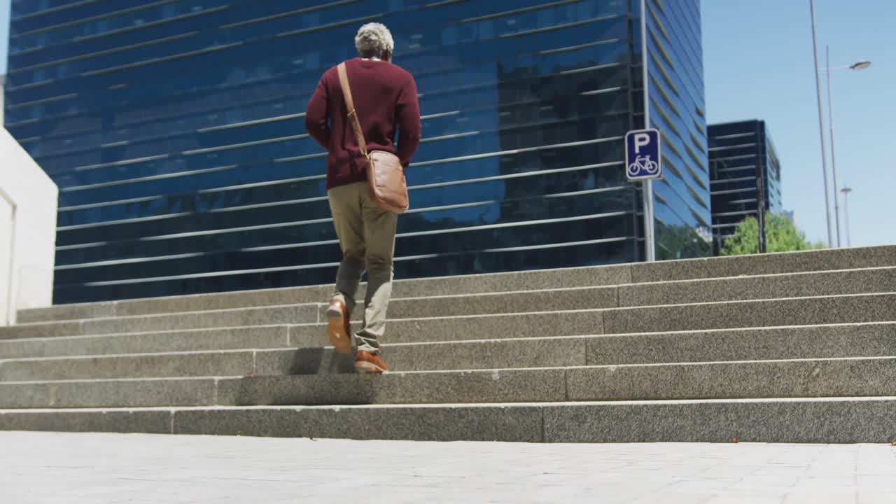 vista trasera de un hombre mayor afroamericano subiendo las escaleras en el parque corporativo