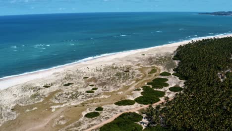 Trucking-left-aerial-drone-shot-of-the-tropical-coastline-of-Rio-Grande-do-Norte,-Brazil-with-a-white-untouched-beach,-blue-ocean-water,-and-palm-trees-in-between-Baia-Formosa-and-Barra-de-Cunha?