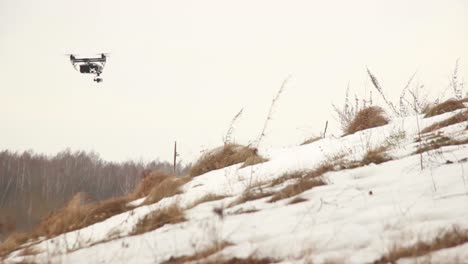 drone profesional dji inspire 2 vuela bajo sobre una colina nevada mientras sopla un fuerte viento