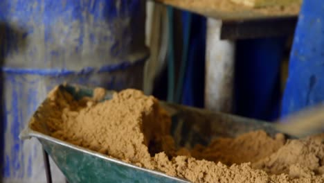 close-up of worker putting soil in metal barrel at workshop 4k