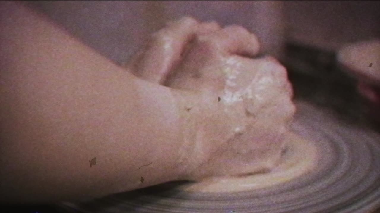 A potter teaches a woman to make clay dishes. A man takes a woman's hands. Vintage effect.