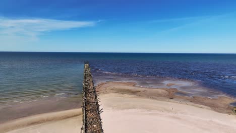 the remains of what used to be an old bridge built on stone and wooden piles to the baltic sea