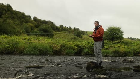 disparo estático de un pescador de mosca lanzando su línea en un río de flujo rápido