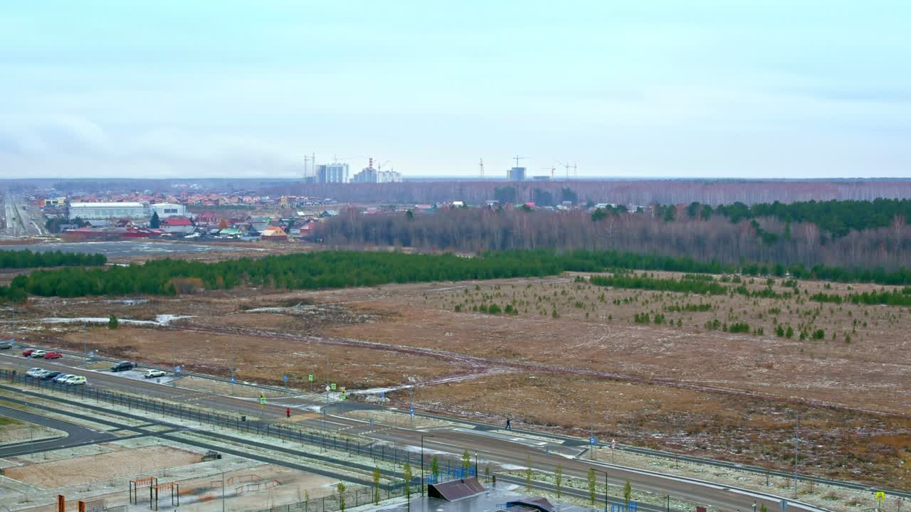 автомобили ездят по дороге, первый снег выпадает на улицы города и покрывает землю и парк в жилом районе города.