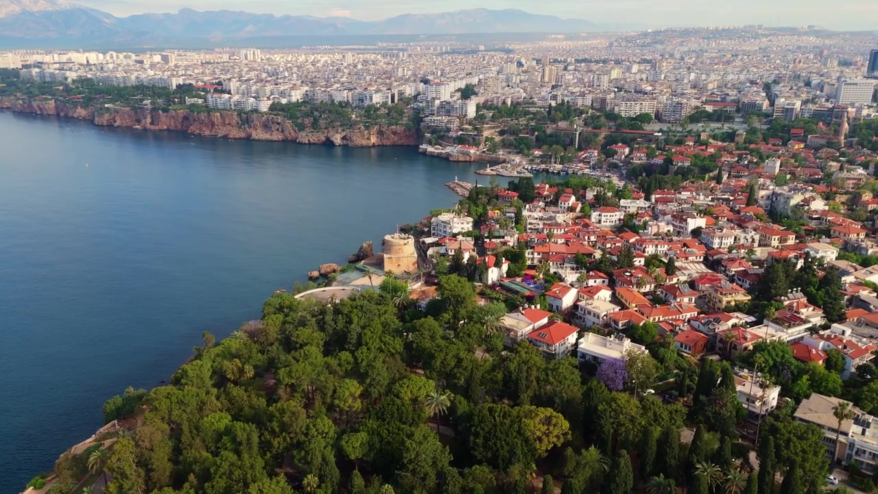 Ripresa aerea con drone delle scogliere costiere di Antalya coperte da alberi verdi vicino al centro storico di Kaleici. Architettura scenografica di città resort mediterranea e paesaggio di viaggio estivo in Turchia.