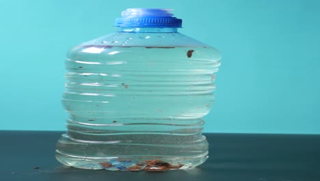 una botella de agua de plástico con una tapa azul y agua clara en el interior