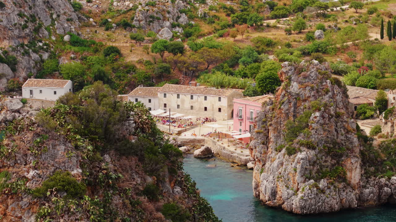Tourists, crystal waters and greenery at the Tonnara di Scopello In The Small Bay Of Sicily, Italy. Aerial Drone Shot