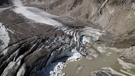 aerial shot of oldest pasterze glacier covered in debris at the foot of grossglockner mountain, melting glacier due to global warming