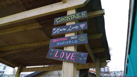 un pequeño bar al aire libre junto a la playa tiene letreros divertidos para la gente que sale de fiesta