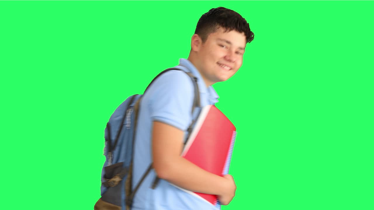 Happy schoolboy showing thumbs up at green screen