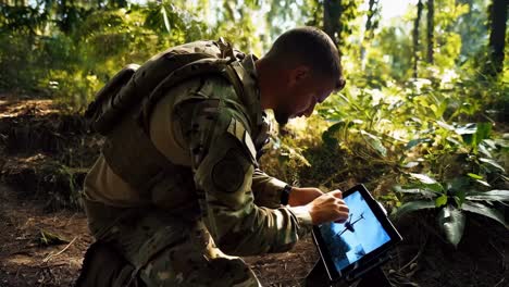 military personnel in training, using a tablet in a forest environment